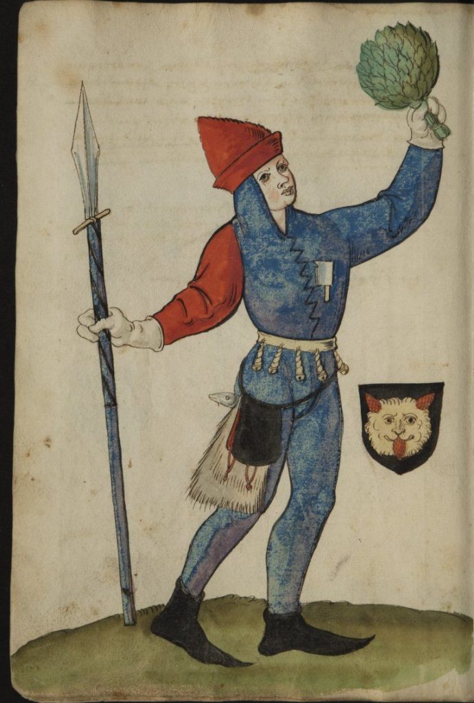 A masked man holding a lance in one hand and a green bushel of branches in the other.